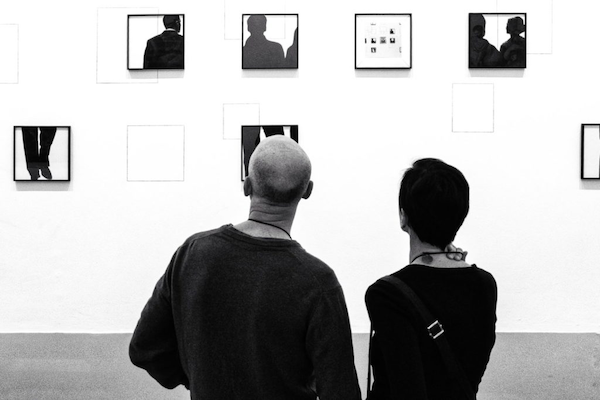 Kunstinteressierte betrachten interessiert ein Werk auf einer Kunstmesse